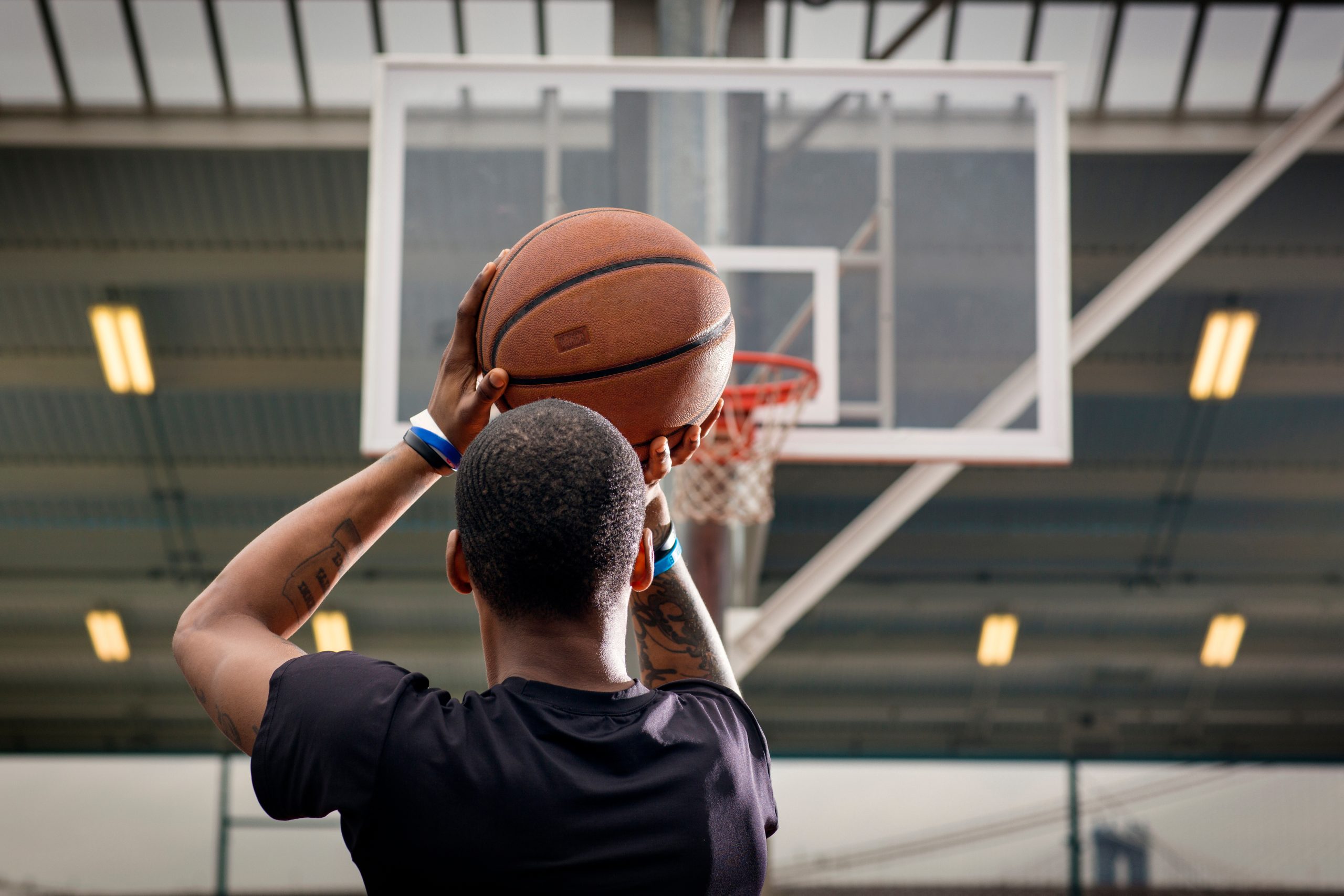 Vista traseira de um jovem a lançar uma bola de basquetebol para o cesto