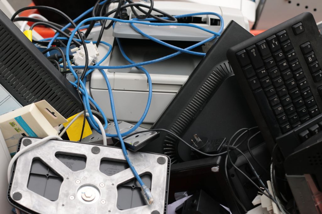 Imagem de lixo eletrónico com monitores, cabos e outros equipamentos ao molho