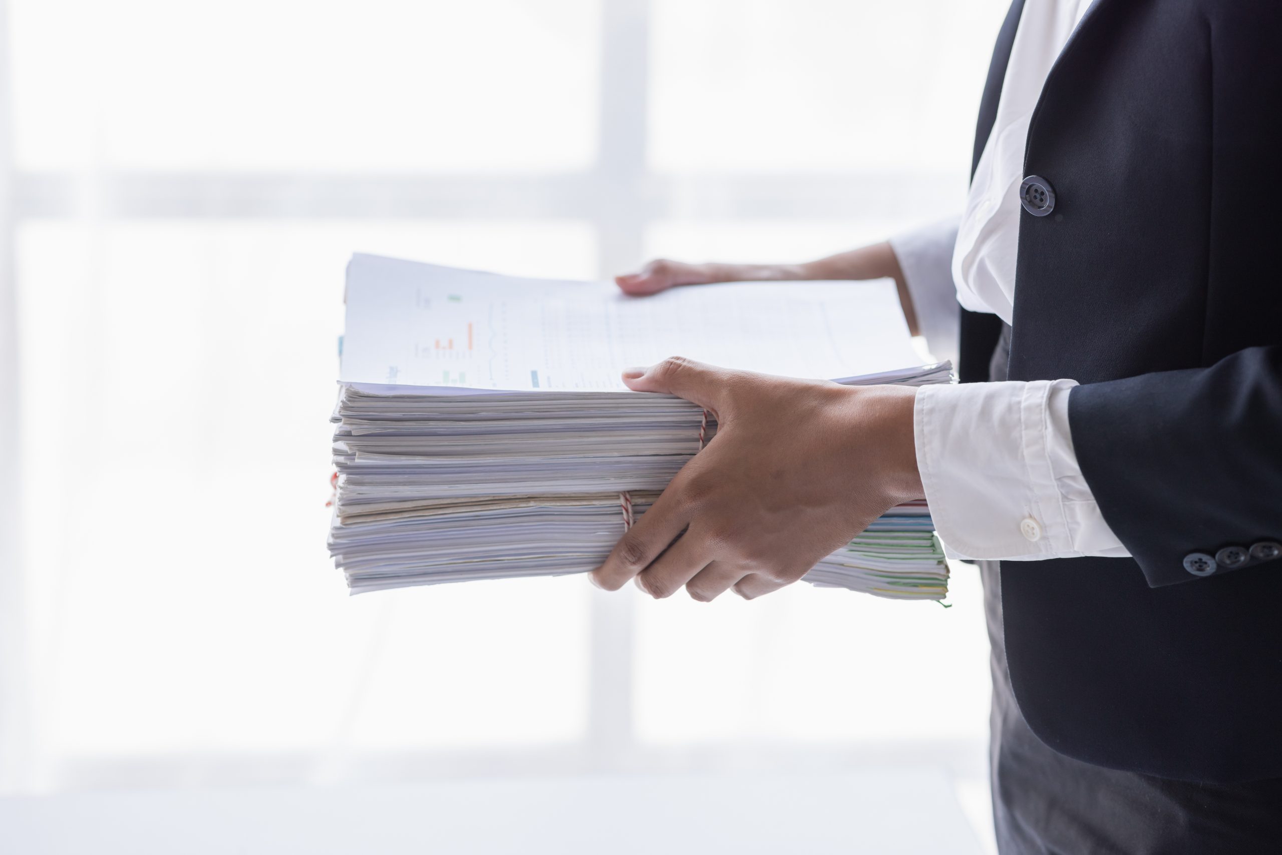 Funcionária a trabalhar com pilhas de arquivos em papel. Conceito de documentos autárquicos.