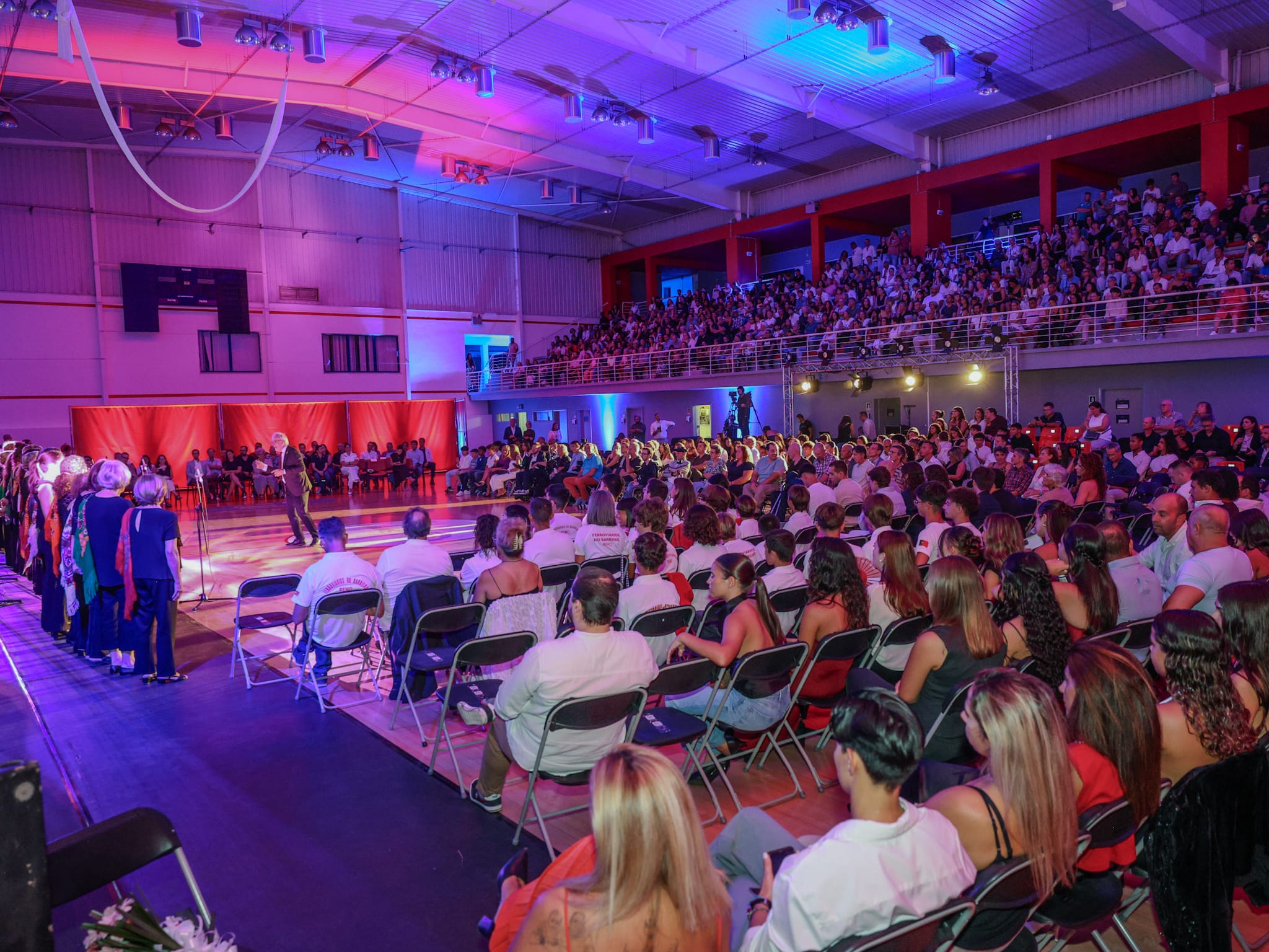 Imagem do público e perspectiva lateral da atuação do Coral TAB na Gala do Desporto 2026